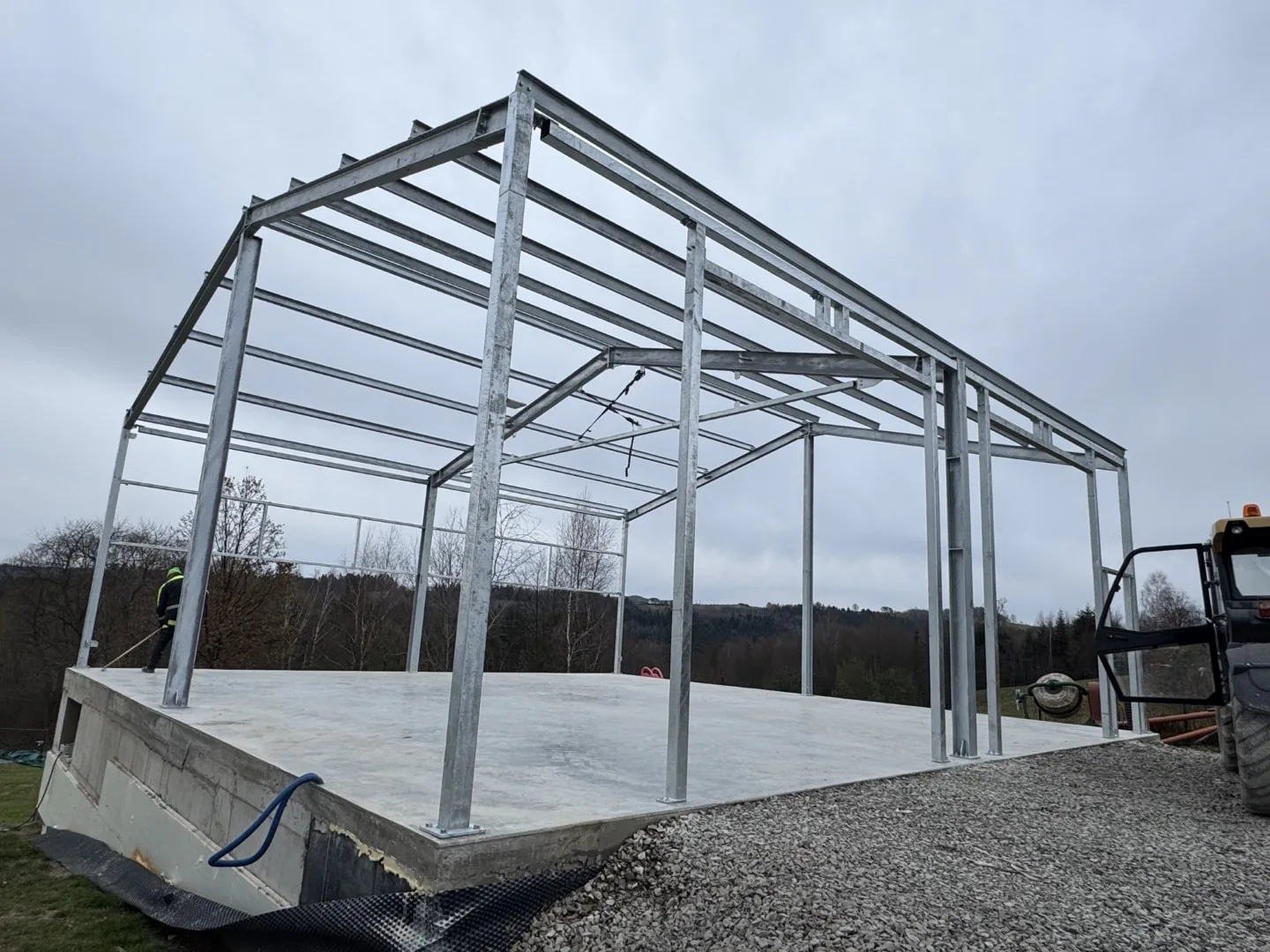 Stalowy szkielet hali na podniesionej płycie fundamentowej, początek montażu słupów i rygli