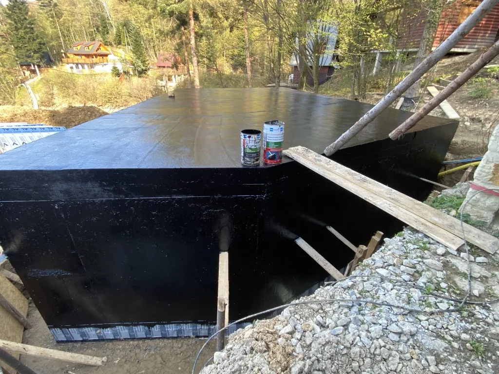 Fundament piwnicy pokryty czarną powłoką hydroizolacyjną od zewnątrz