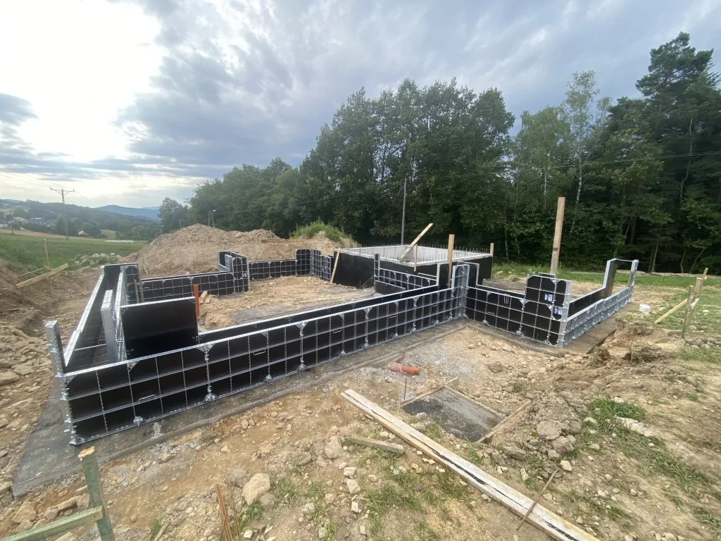Systemowe szalunki rozstawione po obwodzie fundamentu domu, gotowe pod betonowanie