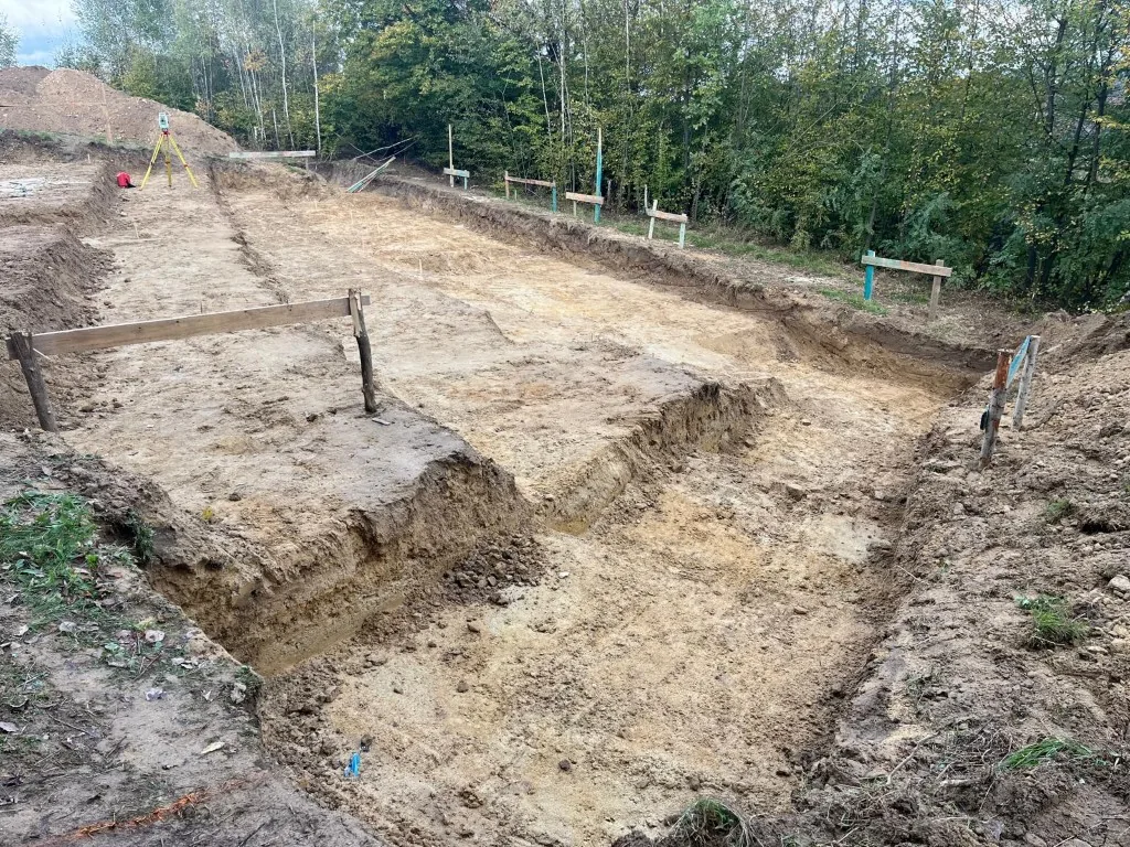 Tachimetr na statywie na stromej działce w Rożnowie, ława ciesielska na pierwszym planie