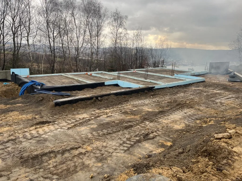 Gotowe fundamenty domu z niebieską izolacją krawędziową, z widokiem na Jezioro Rożnowskie